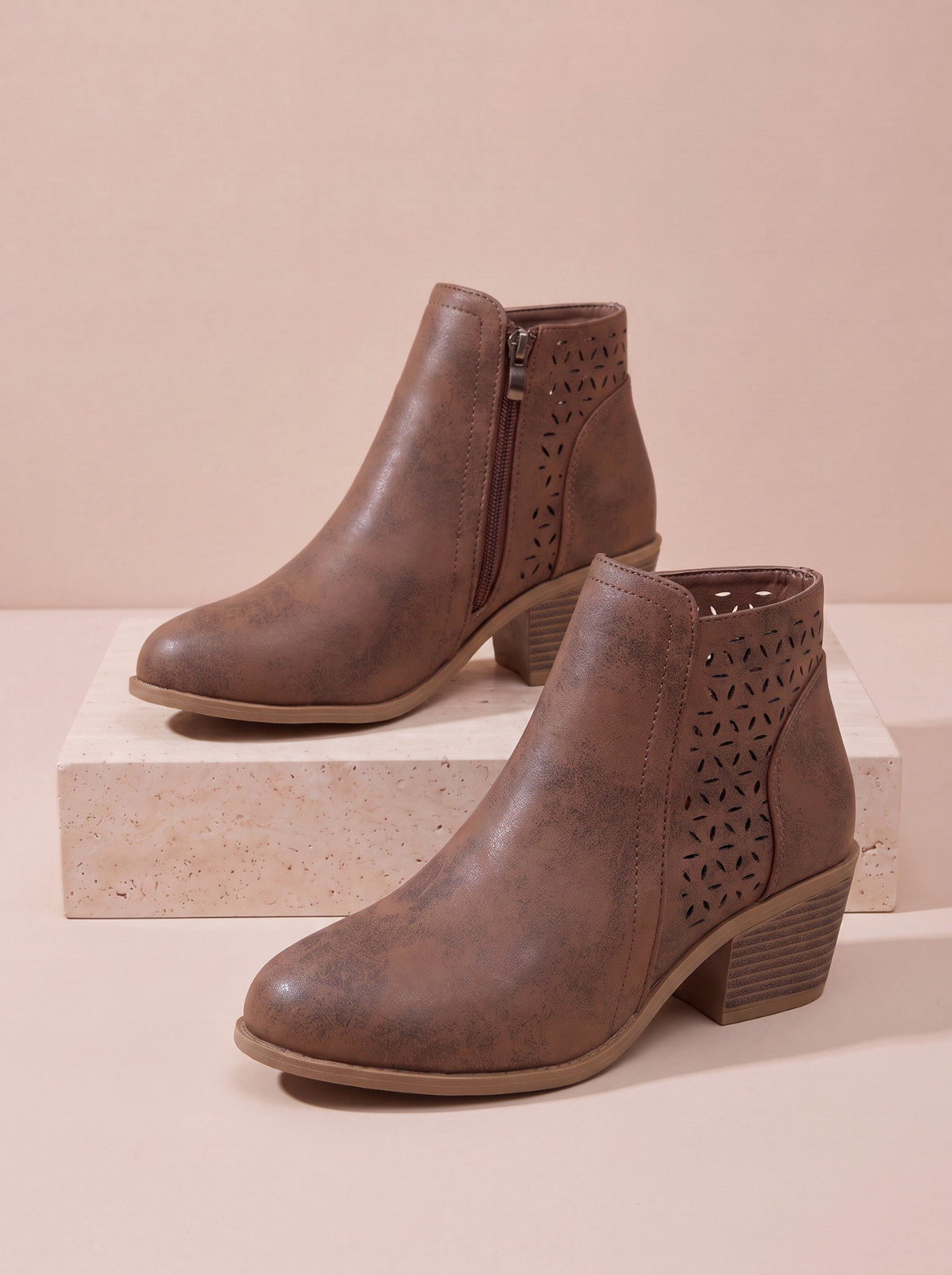 on the sides and a stacked block heel, displayed on a light beige