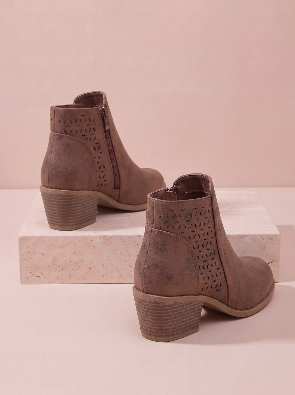 A pair of women's brown ankle boots with laser-cut geometric patterns