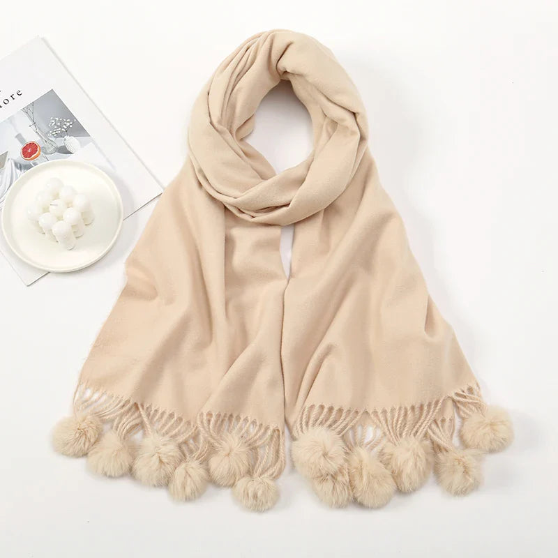 Cashmere scarf with pom pom detail worn over shoulders