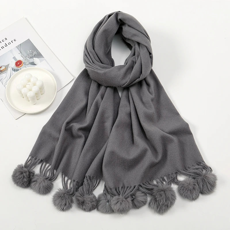 Cashmere scarf with pom pom trim shown in lifestyle setting
