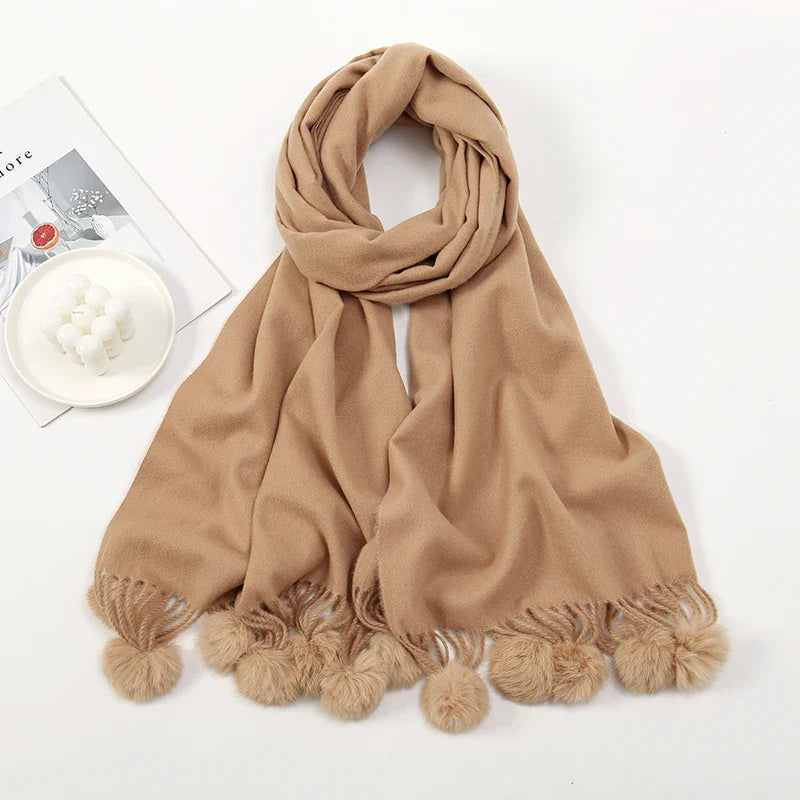 Cashmere scarf with pom pom detail worn over shoulders