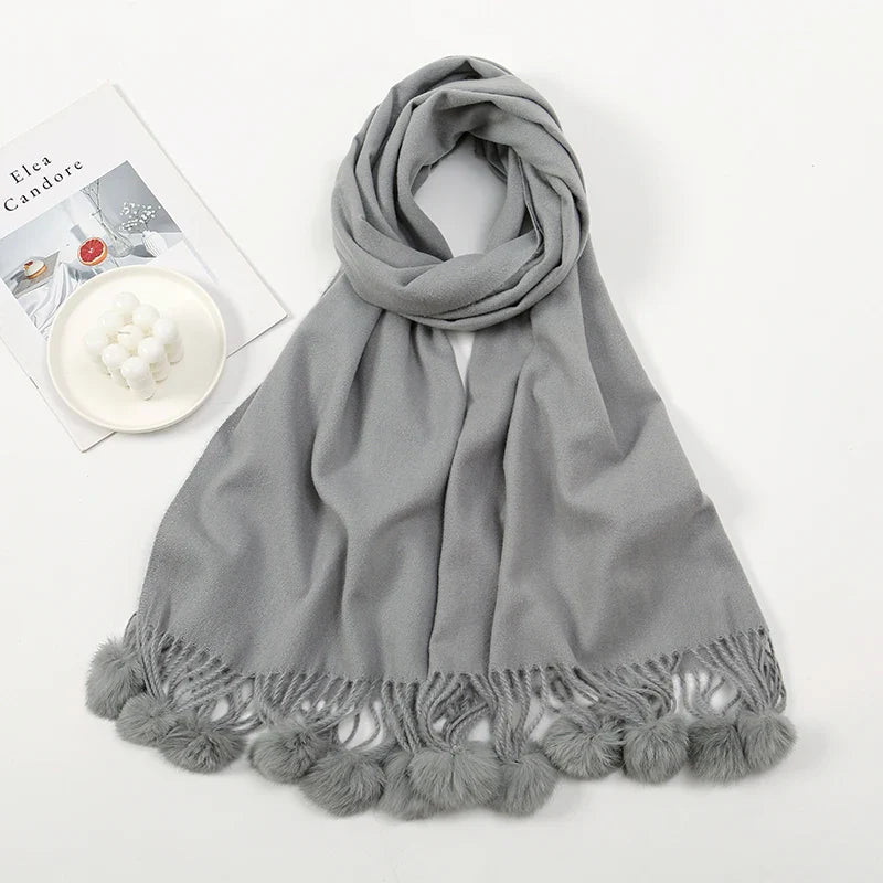 Cashmere scarf with pom pom embellishment shown in close-up detail