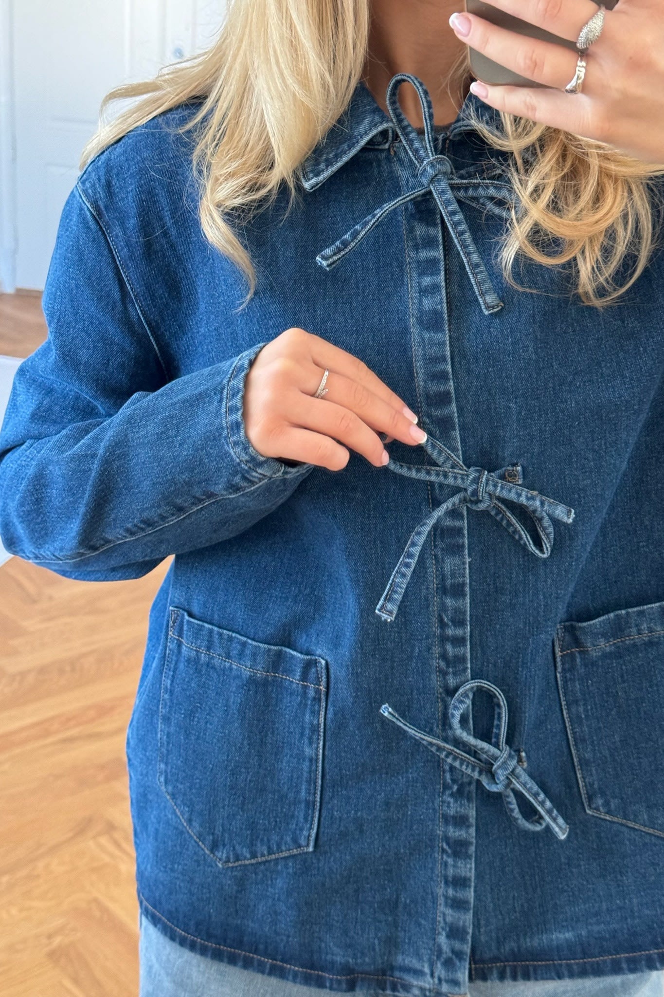 Close-up detail of tie waist closure on women's cotton denim jacket