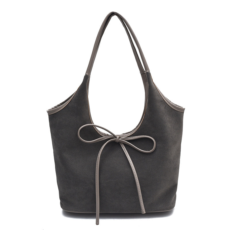 Suede handbag displaying side view and strap attachment