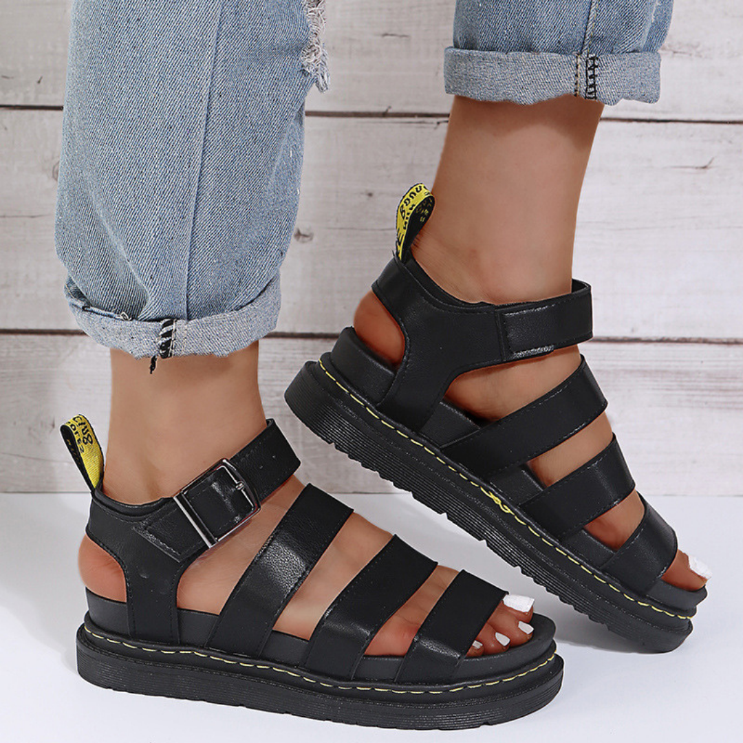 Black open-toe women's sandal with buckle strap detail and thick platform sole, angled view