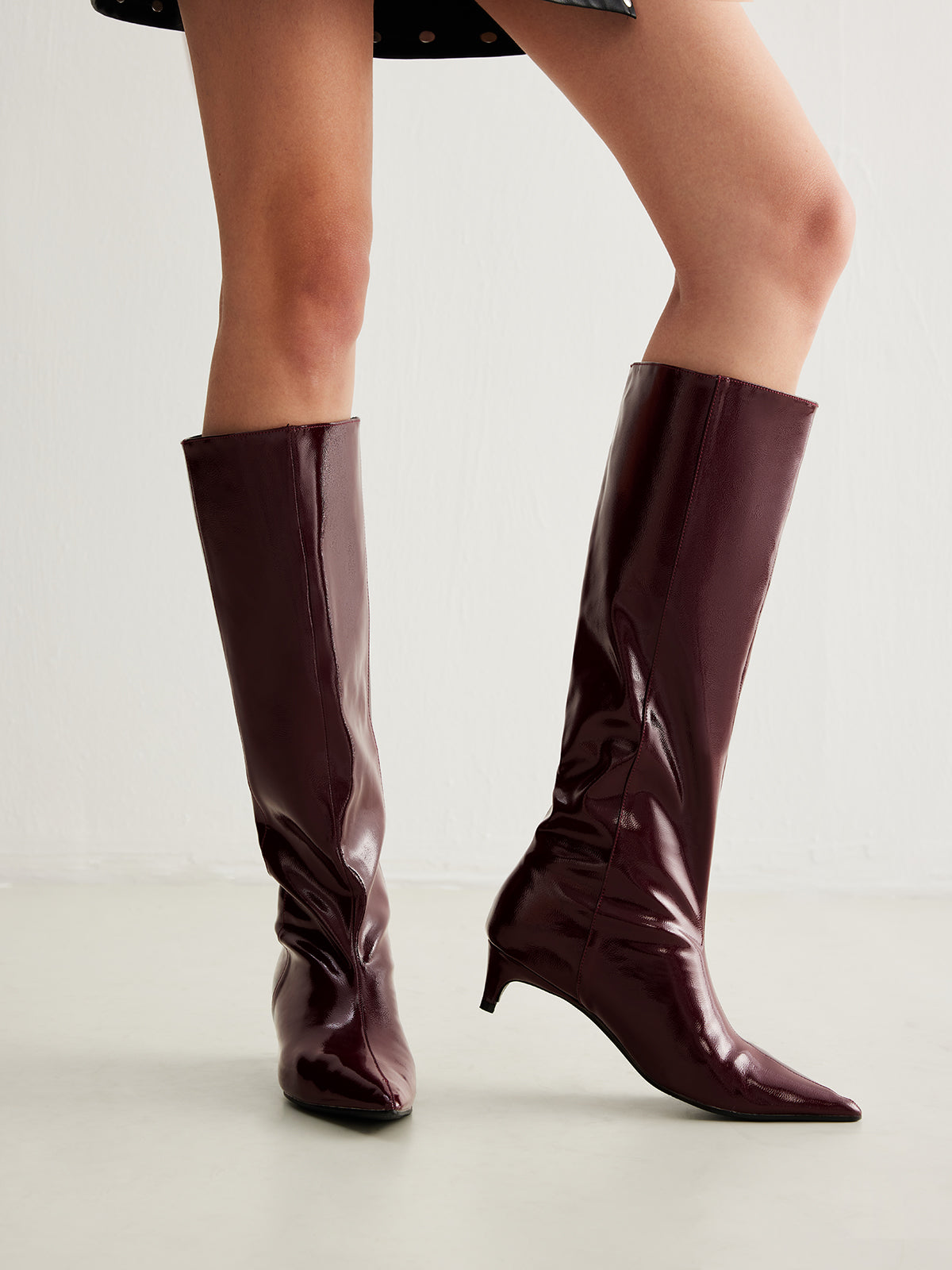 patent knee high boots with pointed toe and slim fit on white background