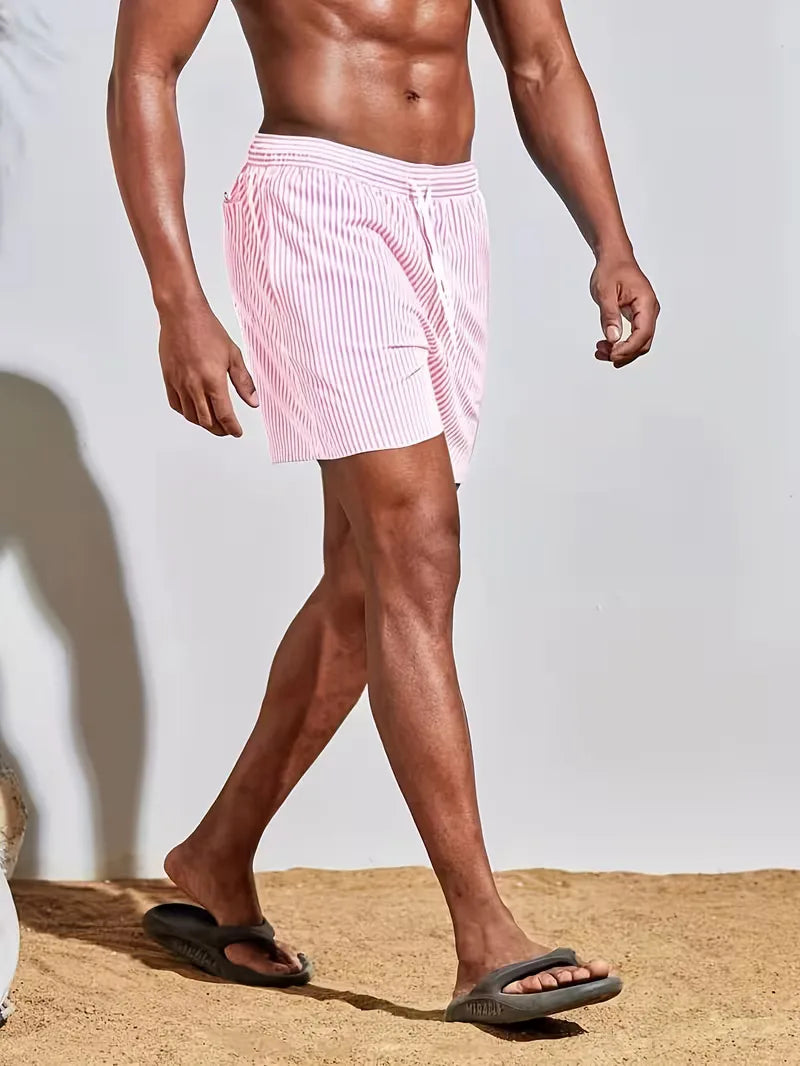 Person wearing pink striped swim shorts on a neutral background